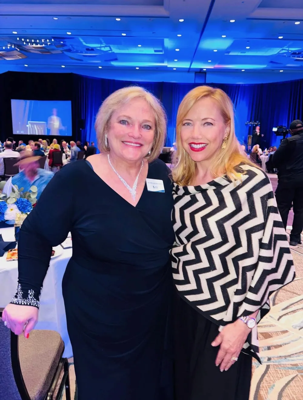 Two guests share a smile in the blue-lit ballroom.