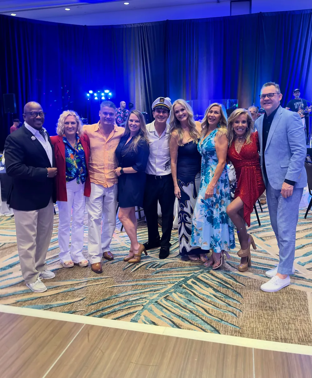 A group of gala guests gathers for a photograph in the ballroom.