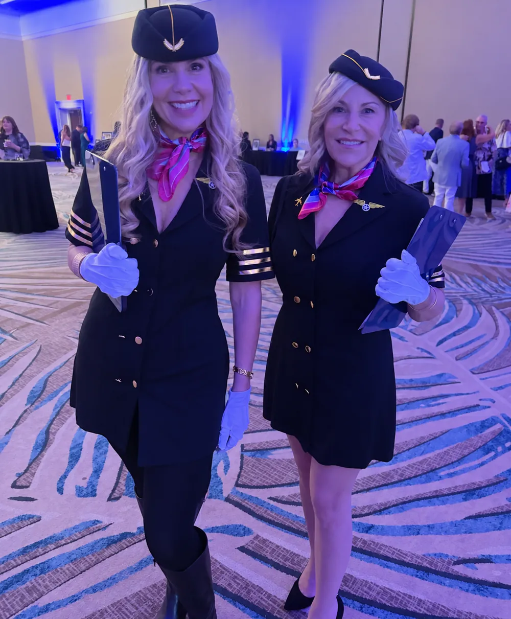 Two guests in flight attendant costumes celebrate the Yacht Rock theme.