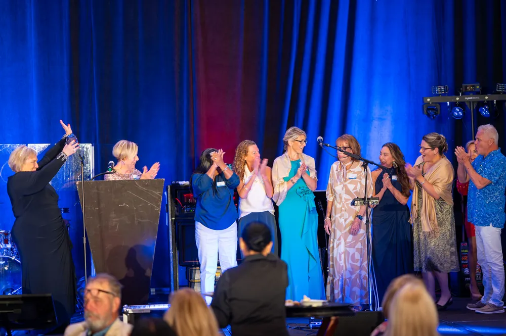 Gala participants celebrate and applaud together on stage.
