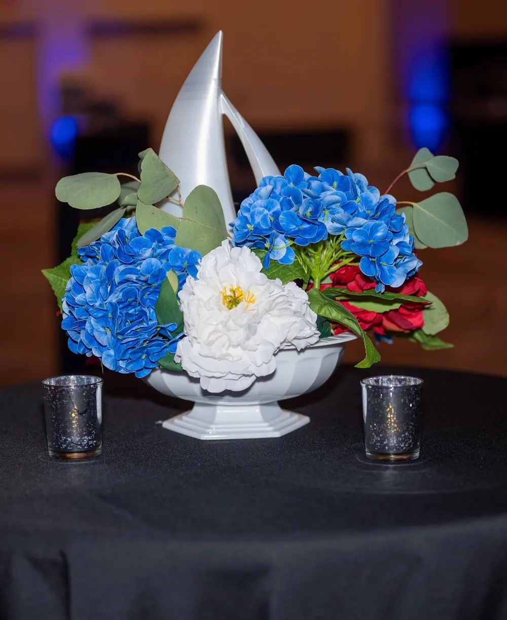 Blue and white flowers and a sailboat decorate a gala table.
