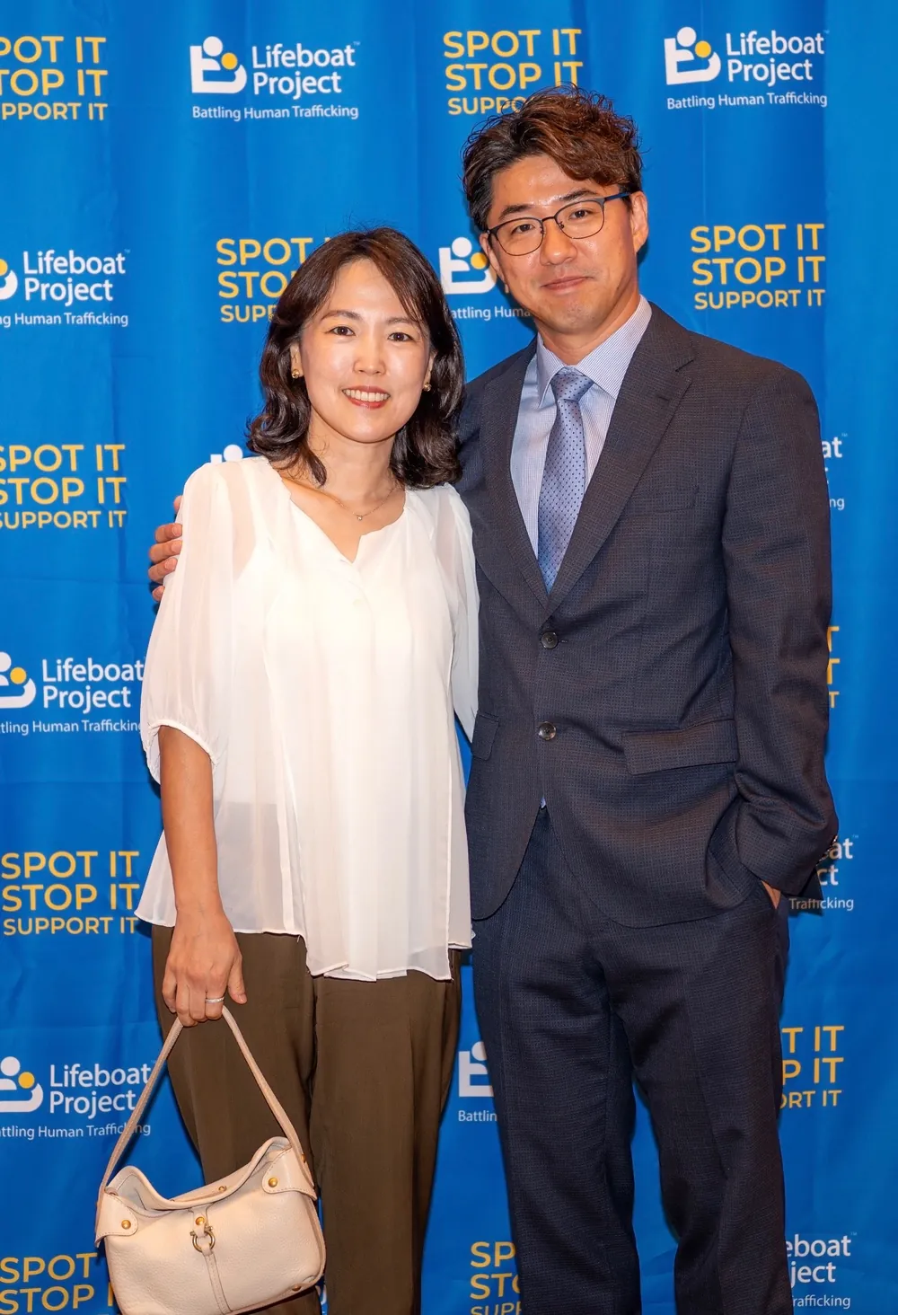 Guests in a white dress and dark suit pose for a photograph.