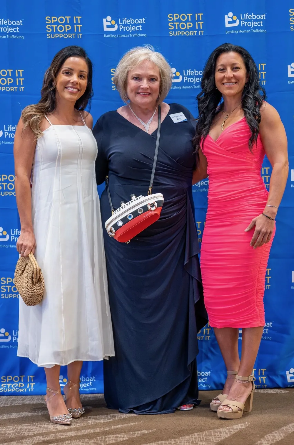 Three guests pose together, including a guest holding a sailboat purse.